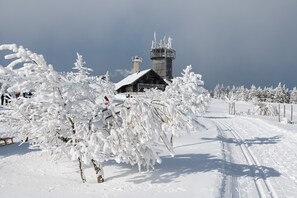 A snow-covered landscape with a wooden cabin and a tower structure. - Apartment 'Ferienwohnung Tannenblick 3-4' with Mountain View, Balcony and Wi-Fi (Oberhof)