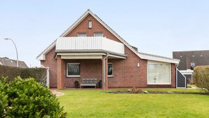 Una casa in mattoni con un balcone, un cortile anteriore e un garage.