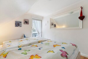 Une chambre avec deux lits, un grand miroir et une fenêtre avec des rideaux.