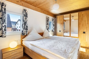 Une chambre à coucher avec un lit en bois, des tables de chevet, une commode, un miroir et une armoire.