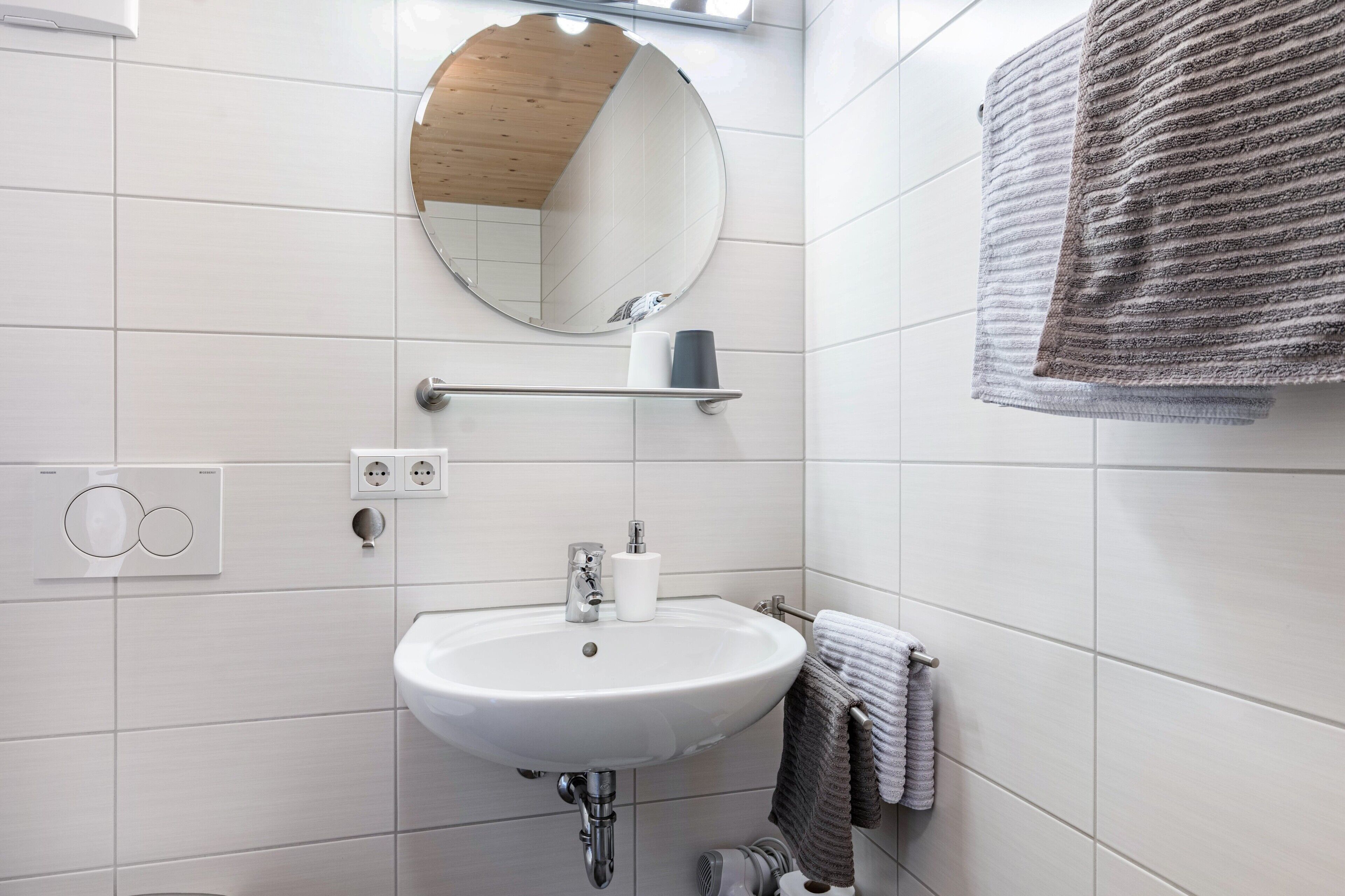A bathroom with a white sink, a mirror, a towel rack, and a towel.