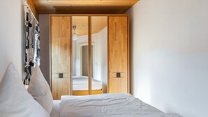Ein Schlafzimmer mit Bett, weißer Bettwäsche, einem Holzschrank und einer Wandleuchte.