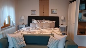 A bedroom with a bed, two bedside tables, a radiator, a window with curtains, and a door leading to a bathroom. - Apartment 'Mina' with Shared Terrace, Shared Garden and Wi-Fi (Leibertingen)