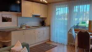 A compact kitchen with a dining area, a television, and a view of the outdoors. - Apartment 'Mina' with Shared Terrace, Shared Garden and Wi-Fi (Leibertingen)