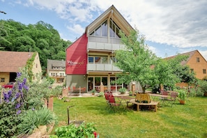 A two-story building with a red section, a balcony, and a garden with outdoor seating. - Apartment "Riesling" with Balcony and Wi-Fi (Brackenheim)