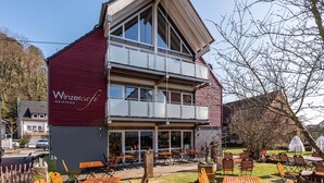 Un edificio de dos pisos con fachada roja y un balcón, identificado como 'Winzercafe NEIPPERG'.