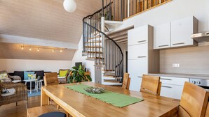 Una cocina moderna con armarios blancos, una mesa de comedor de madera y una escalera en espiral.