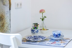A table with a plate, a cup, a vase with a flower, and a small bowl with items.