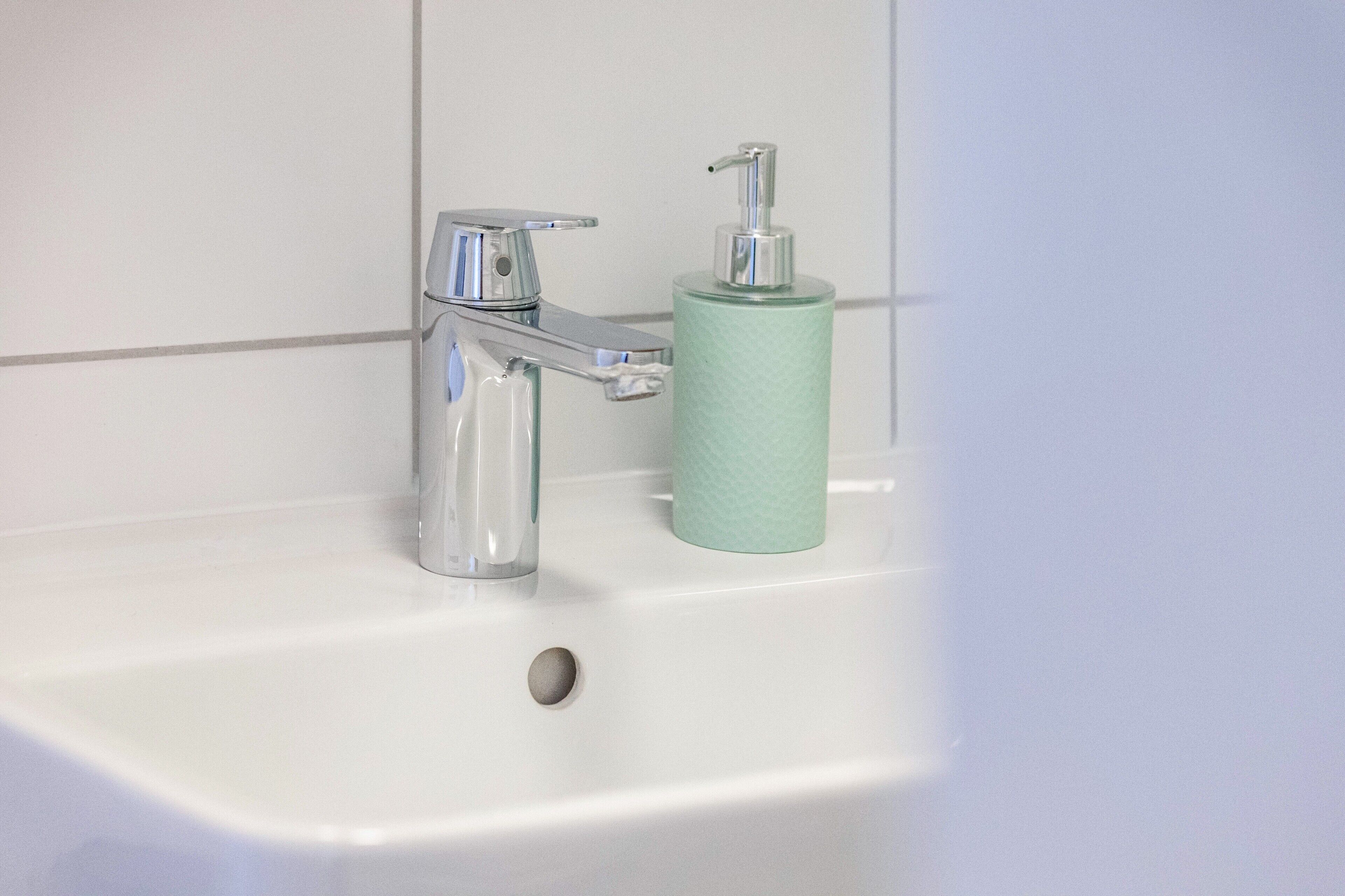 A bathroom sink with a chrome faucet and a soap dispenser.