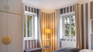 A bedroom with a bed, a chair, a lamp, and a window with curtains. - Apartment '21' with Mountain View, Shared Terrace and Wi-Fi (Masserberg)