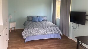 A bedroom with a bed, a TV, a nightstand, and a dresser. - Elysium Retreat & Stays (Bondoola)