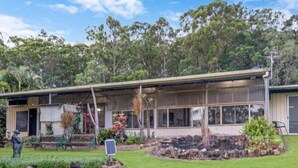 A two-story building with a covered porch and a small garden area with rocks and plants. - Elysium Retreat & Stays (Bondoola)