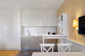 Une cuisine moderne avec des meubles blancs, un évier encastré et un petit coin repas équipé de deux tabourets.