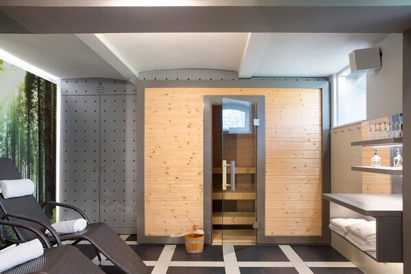 A modern spa room with a sauna, wooden panel walls, a glass door, and a checkered floor.