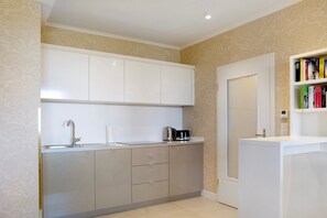 A modern kitchen with white cabinets, a stainless steel sink, and a coffee maker.