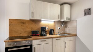 A compact kitchen with a wooden countertop, a built-in oven, a coffee maker, and a sink. - Apartment “Island of Relaxation Bungalow” with Private Terrace, Garden & Wi-Fi (Milmersdorf)