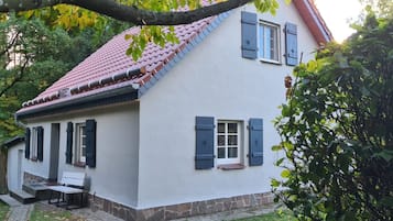 A two-story house with a red-tiled roof, white walls, and dark shutters.