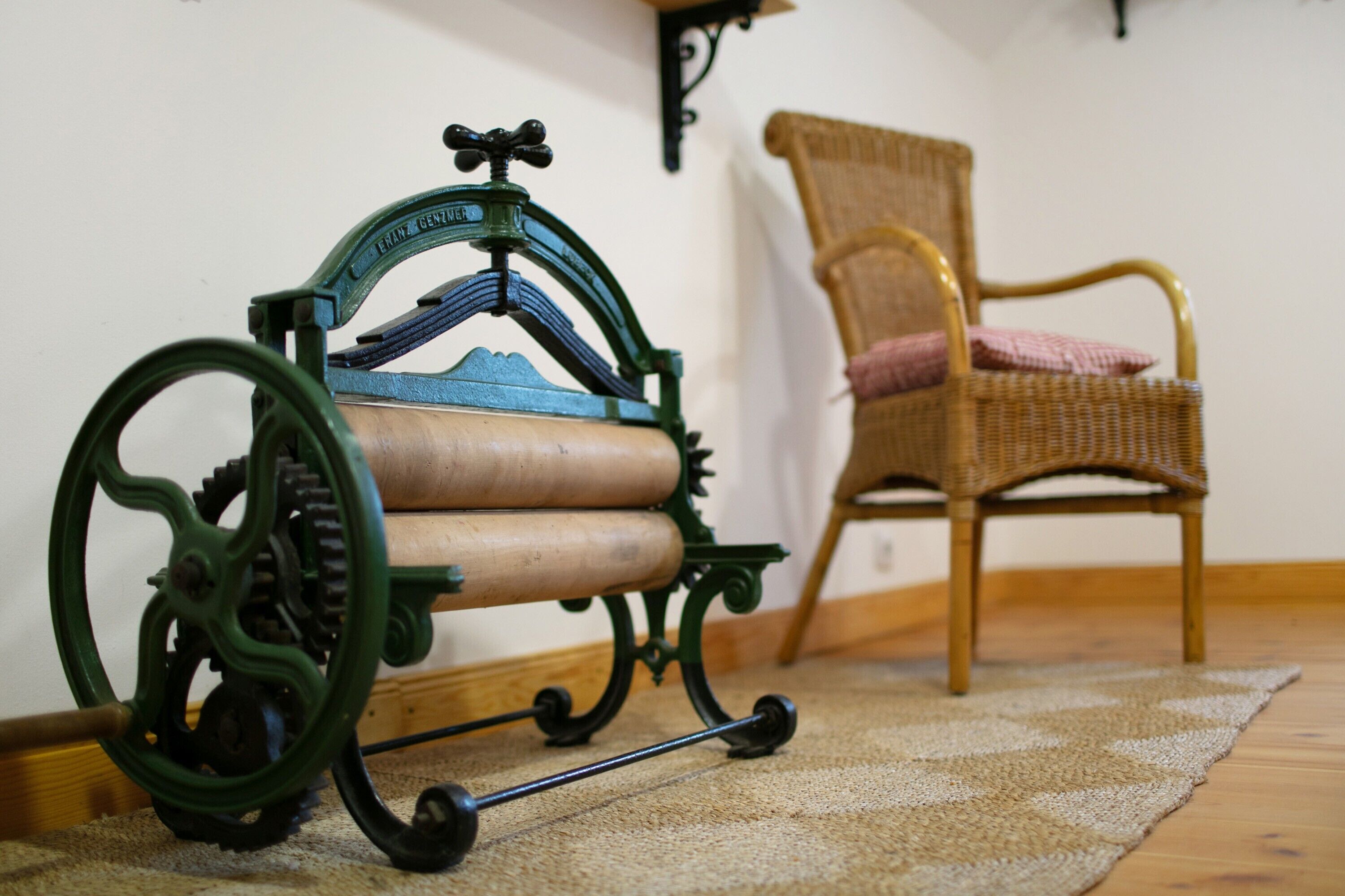 A vintage sewing machine, a wicker chair, and a wooden floor.