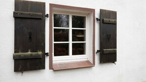 Una ventana con contraventanas blancas y un pequeño alero.