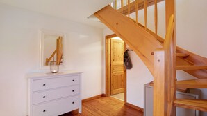 A staircase with wooden railings, a white dresser with drawers, and a door leading to another room. - Apartment 'Haus Am See - Zur Roten Tür' with Lake View, Private Terrace and Wi-Fi (Templin)