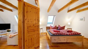 A bedroom with a wooden bed, a TV, a desk, and a window. - Apartment 'Haus Am See - Zur Roten Tür' with Lake View, Private Terrace and Wi-Fi (Templin)
