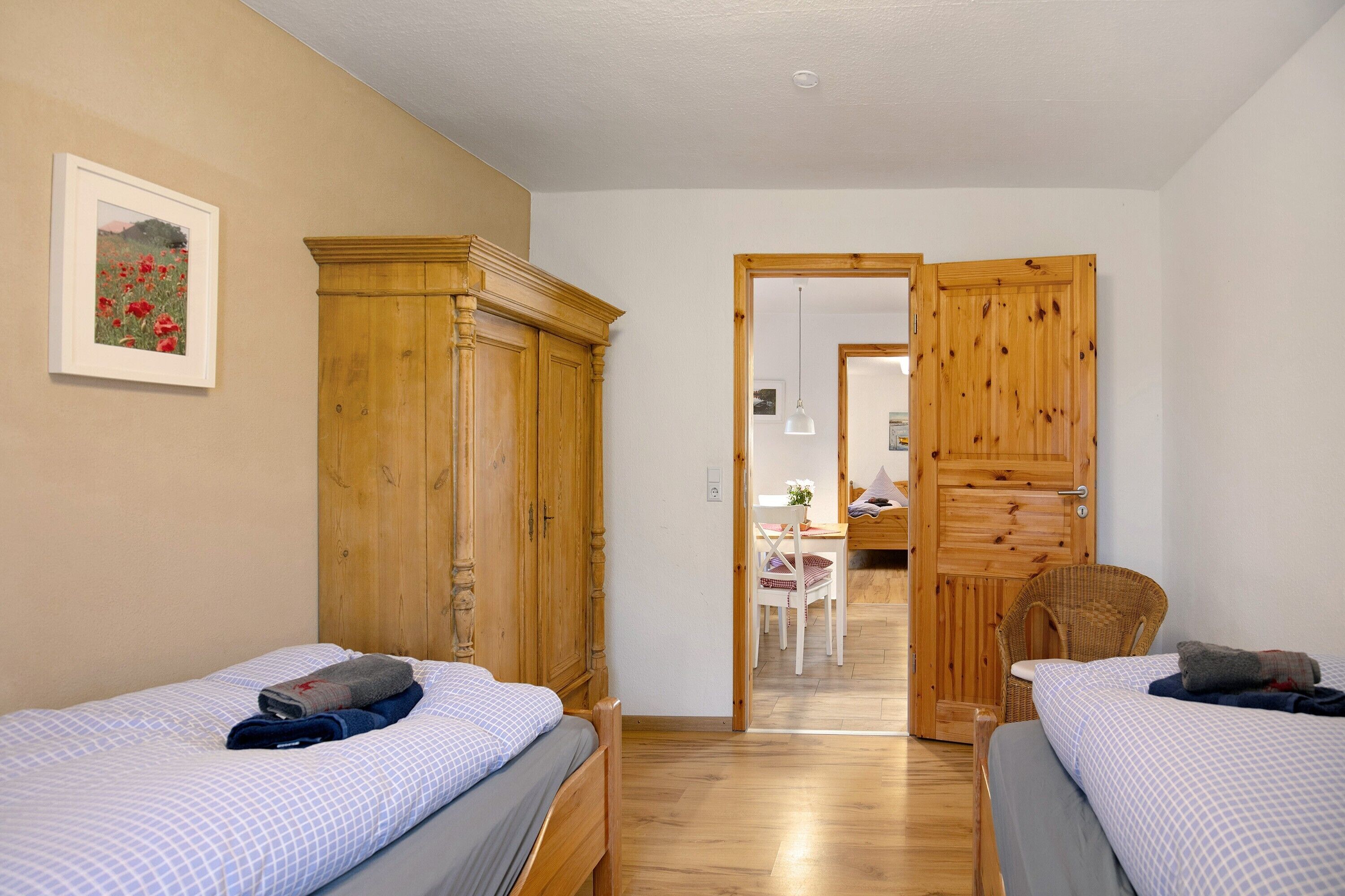 Une chambre avec deux lits, des armoires en bois, un bureau et une chaise.