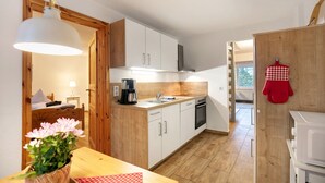 A compact kitchen with wooden cabinets, a sink, a stove, and a microwave. - Apartment 'Haus Am See - Zur Blauen Tür' with Lake View, Private Terrace and Wi-Fi (Templin)