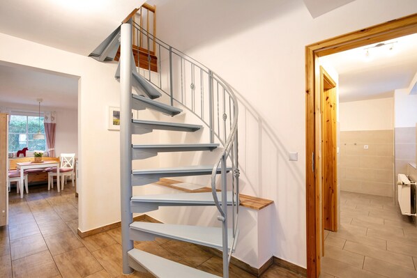 A spiral staircase with metal railings and wooden steps, leading to an upper floor.