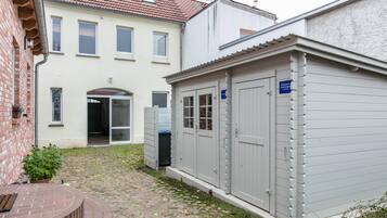Une cour avec un chemin pavé de pierres, un banc en briques et un petit jardin.