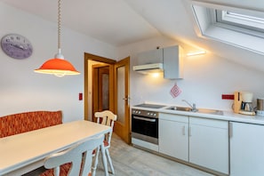 A kitchen with a stove, oven, sink, and a clock on the wall. - Haus Erika - Apartment 3 with Wi-Fi, Balcony & Shared Garden near Skywalk (Willingen (Upland))
