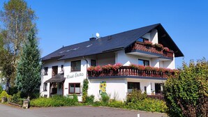 A two-story building with a sign 'Haus Erika' and a balcony with flowers.