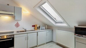 A modern kitchen with a skylight, built-in oven, and white cabinetry.
