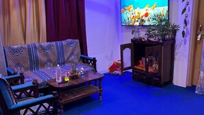 Un salon comprenant un canapé, une table basse, un téléviseur et une petite étagère ornée d’objets décoratifs.