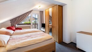 Ein Schlafzimmer mit zwei Betten, einem Fernseher, einem Holzschrank und einem Balkon mit Blick.