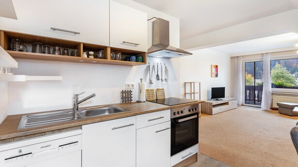 Eine moderne Küche mit weißen Schränken, einer Holzausziehtafel, einem eingebauten Ofen und einem großen Fenster.