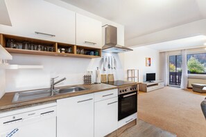 Una cocina moderna con armarios blancos, encimera de madera, horno empotrado y un amplio ventanal.
