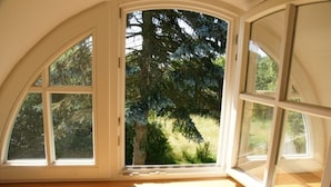 Una habitación con un amplio ventanal de arco, suelo de madera y vistas a árboles.