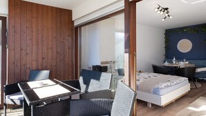 Une pièce comprenant un lit, une table avec des chaises, un bureau et une fenêtre avec des stores.