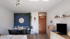 Une chambre moderne équipée d’un lit, d’un bureau avec des chaises, d’une télévision et d’une porte.