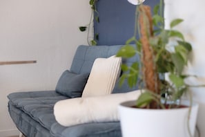 Un canapé bleu avec un coussin blanc, une plante en pot et un mur agrémenté d’une touche de bleu.