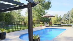A swimming pool with a pergola, lounge chairs, and a fenced backyard. - The Orchard & Oak Apartment - Pool, Peaceful, Perfect. (Te Puke)