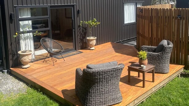 A modern house with a wooden deck, wicker furniture, and potted plants. - The Orchard & Oak Apartment - Pool, Peaceful, Perfect. (Te Puke)