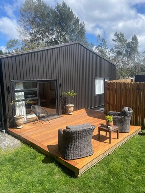 A modern house with a wooden deck, wicker furniture, and potted plants.