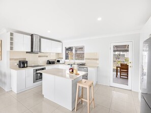 A modern kitchen with white cabinetry, a central island, and a view to the outside.