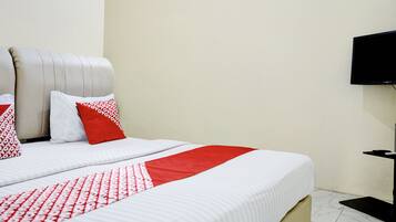 A hotel room with a bed, pillows, a television, and a small table.
