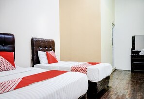 A hotel room with two beds, each with white bedding and red accents, a dark headboard, and a wooden floor. - Hotel O Mantari Guesthouse (Bukittinggi)