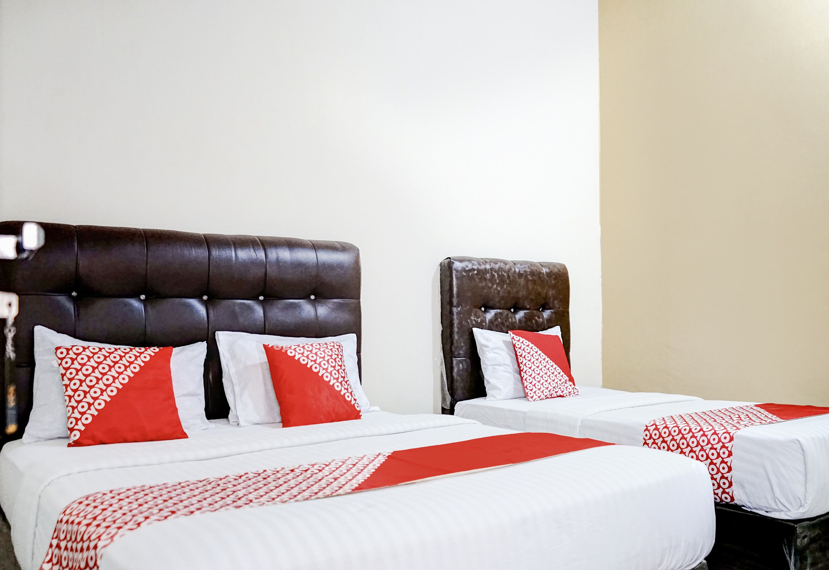 Two twin beds with headboards, white bedding, and red and white patterned pillows.