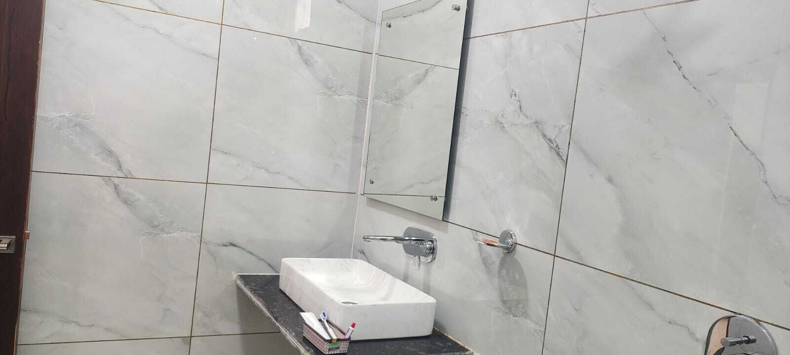 Un baño con suelo de mármol, lavamanos blanco y espejo.