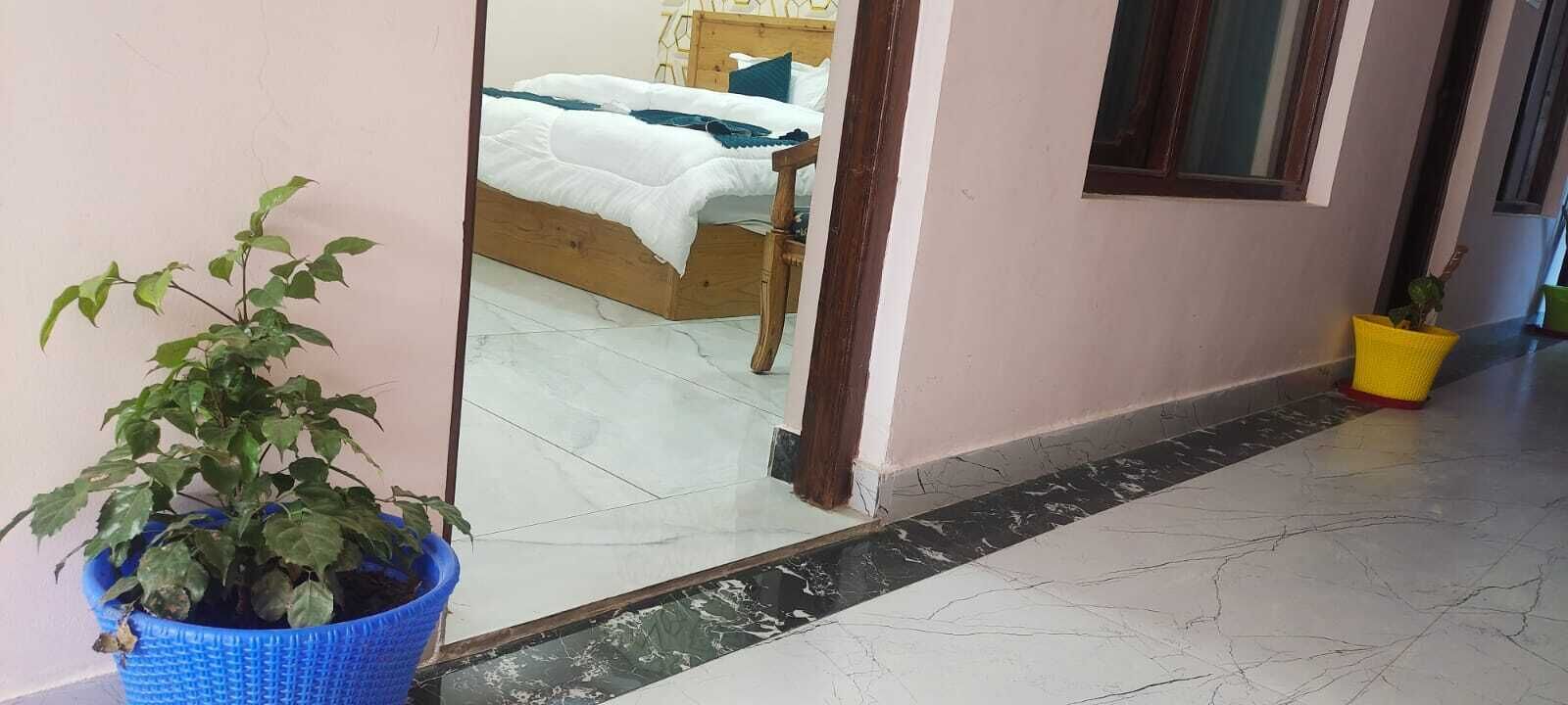 A hallway with a wooden bed, a blue potted plant, and a yellow plant pot.