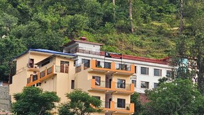Ein mehrstöckiges Hotel mit Balkonen, eine Schilder für 'Hotel Necklace Moon Restaurants' und eine Hügelkulisse.